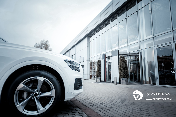 White passenger car standing outside in front of car salon