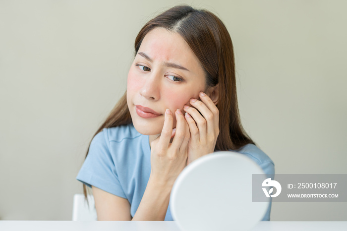 Dermatology, scratch asian young woman looking at mirror, expression worry and itch, itchy allergy or allergic sensitive reaction, red spot or rash on her face. Beauty care from skin problem treatment