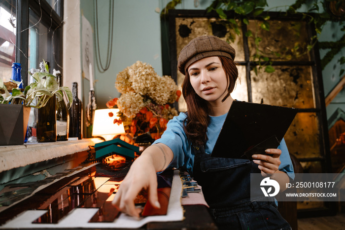 Young woman artist creating stain glass while working in her studio