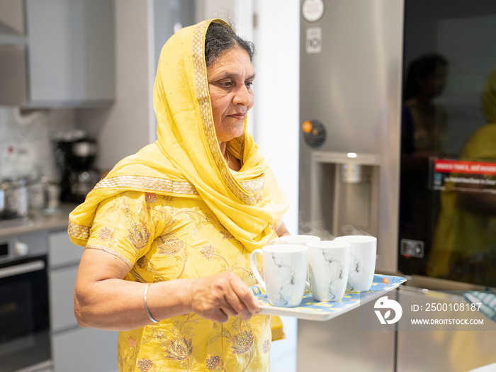 Mature woman in traditional clothing carrying chai