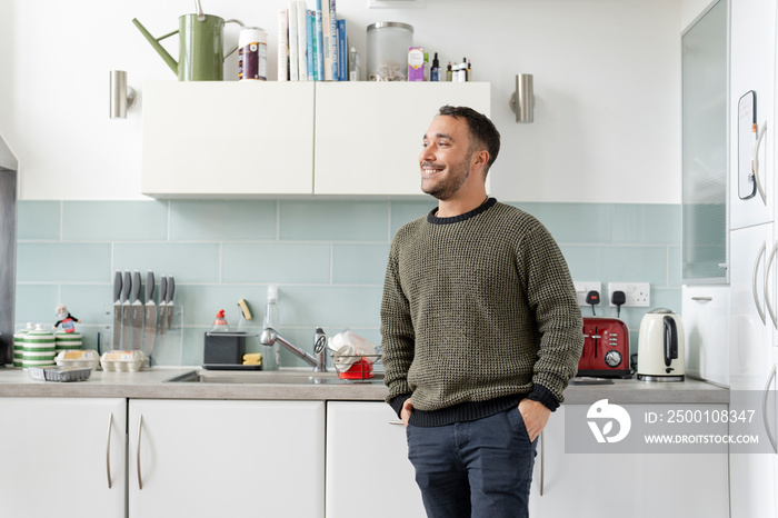 Smiling mature man standing in kitchen at home