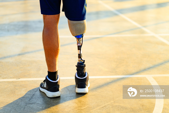 disabled athlete man with prosthetic walking at the beach outdoors at sunset