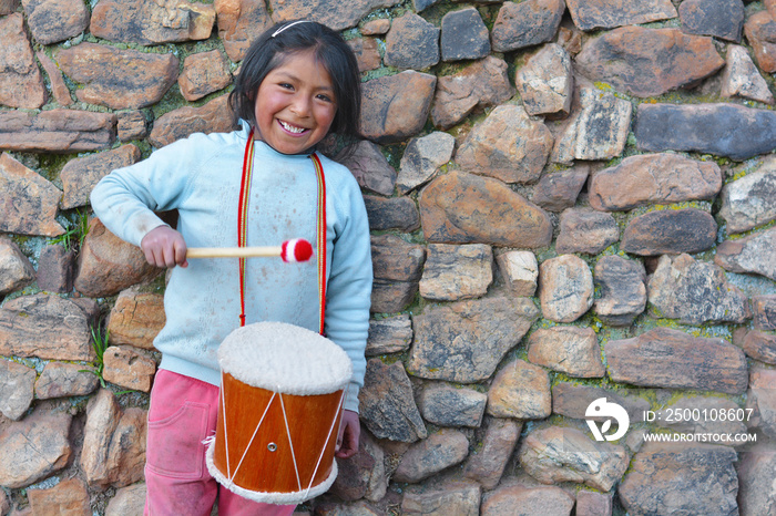 Little native american girl playing traditional sikuri drum.