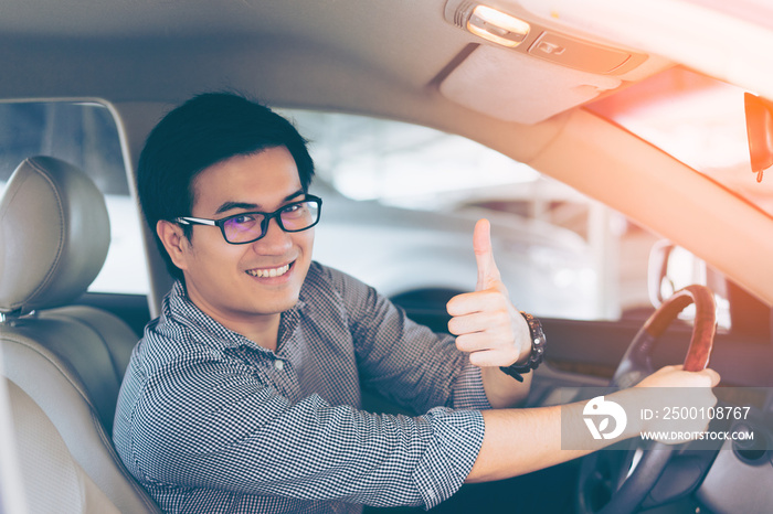 Portrait of asian happy handsome man showing thumbs up while driving car