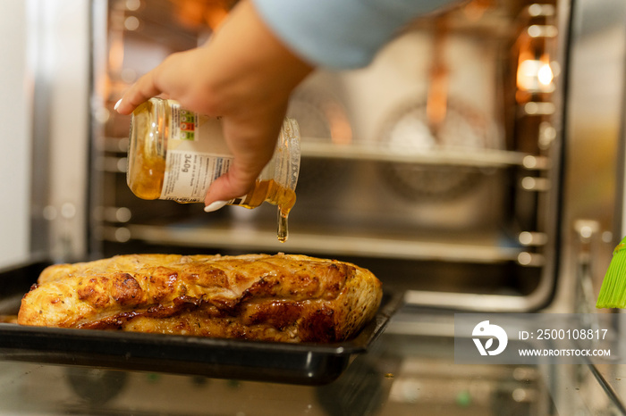 Hand pouring honey over cooked meat