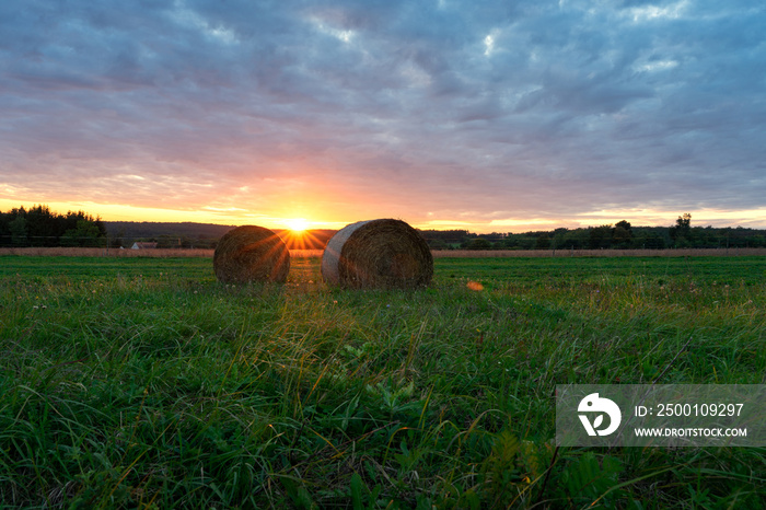 Beautiful sunset on the field in Őrség Hungary with sunbeams and bales