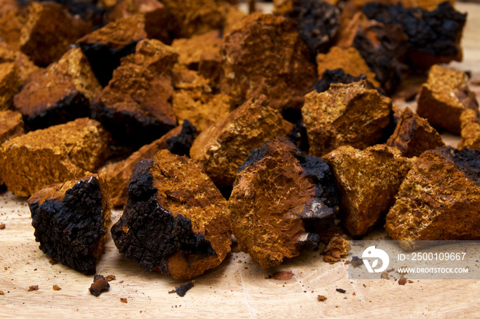 Closeup of dried and cut orange and black medicinal chaga mushroom from birch tree, used in alternative medicine on cutting board.