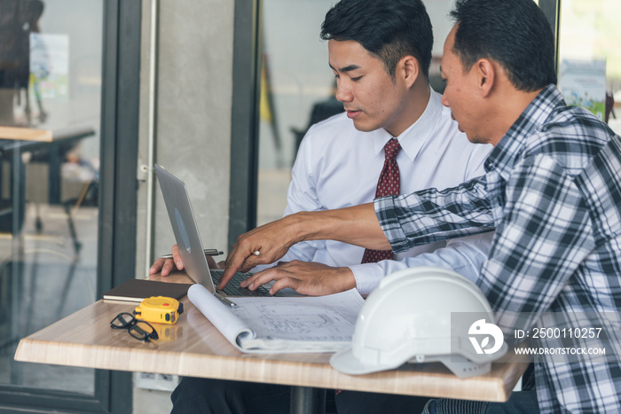 Contractor construction engineer meeting talking together on architect table at construction office site. Businessman engineer manager discuss with foreman team builder look at plan blueprint laptop