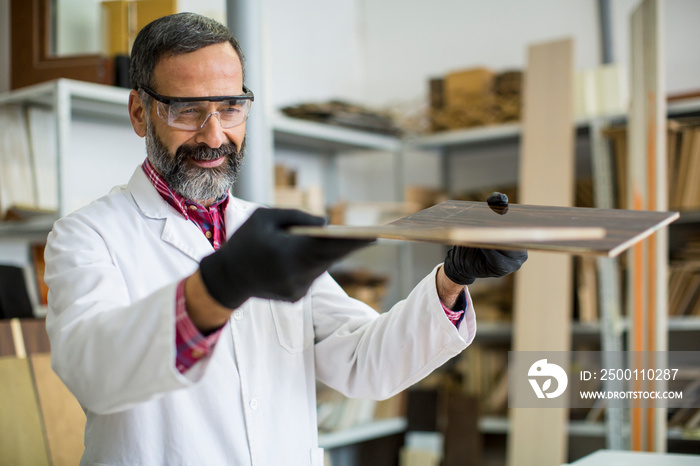 Handsome mature engineer in the laboratory examines ceramic tiles