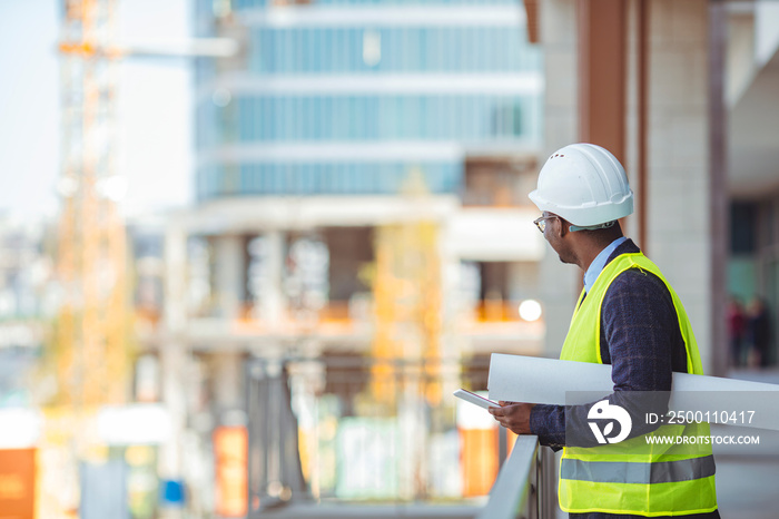 Engineer working on outdoor project. Portrait of an handsome black engineer. Male work building construction engineering occupation project. Engineer with hardhat using tablet pc computer inspecting