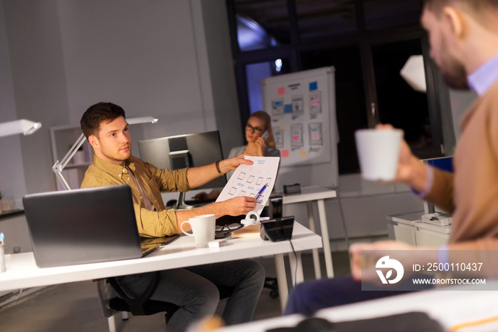 business, deadline and technology concept - software developers discussing user interface design mockup at night office