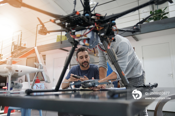 Engineer and technician working together on drone in office