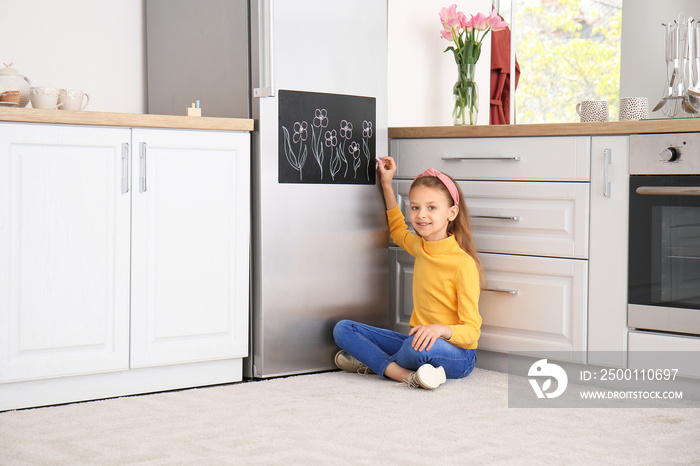 Little girl drawing on chalkboard in kitchen