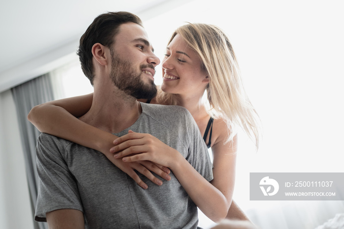 Loving happy couple in love smile and hug each other on the bed, in big bedroom, Love story concept