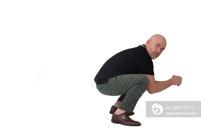 side view of a man looking at camera and sitting squatting on white background