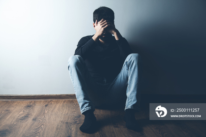 sad man sitting on ground on dark background