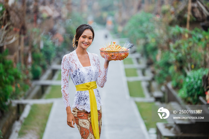 the beauty of balinese woman smiling to camera standing in bali village penglipuran