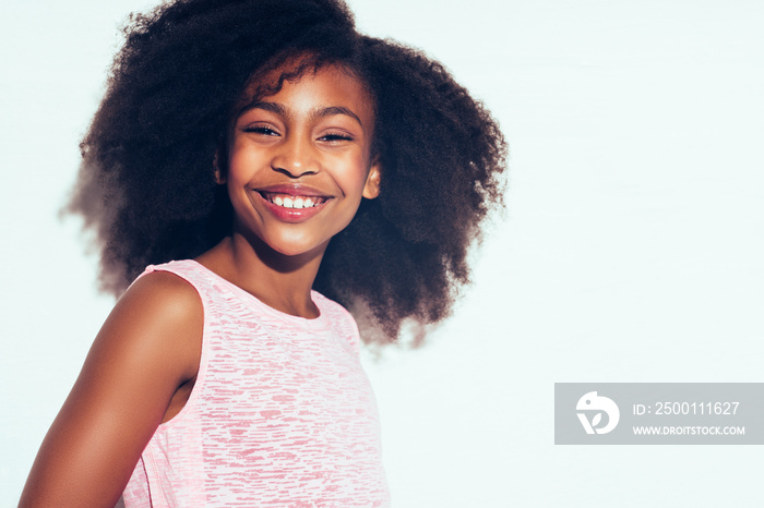 Smiling young African teen standing against a white background