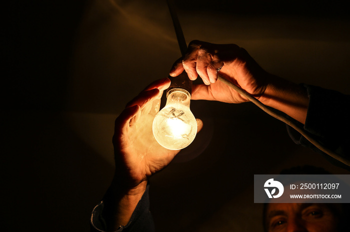 Man is making electricity. Light bulb in workers hand. Maintenance repair works renovation in the flat. Restoration indoors. Light bulb in workers hand.