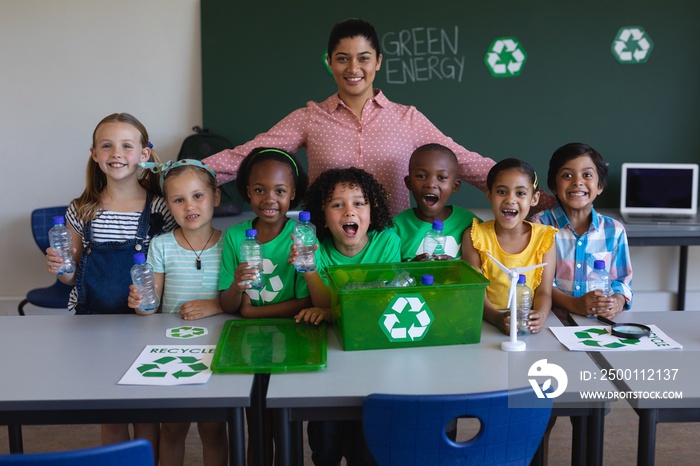 Happy schoolkids and teacher looking at camera in classroom