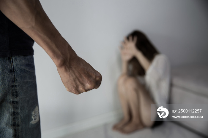 Man beating up his wife illustrating domestic violence. Fear and crying woman beats husband’s abuse. sad and hopeless woman sitting in dark room concept of social problems.