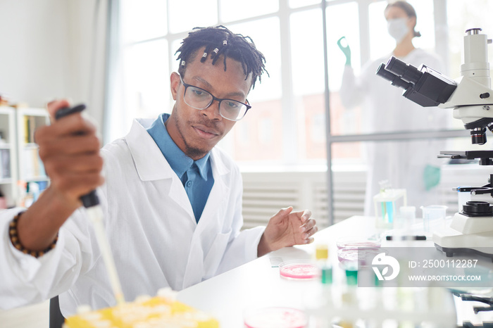 Portrait of young African-American man working in laboratory preparing test samples for research, copy space