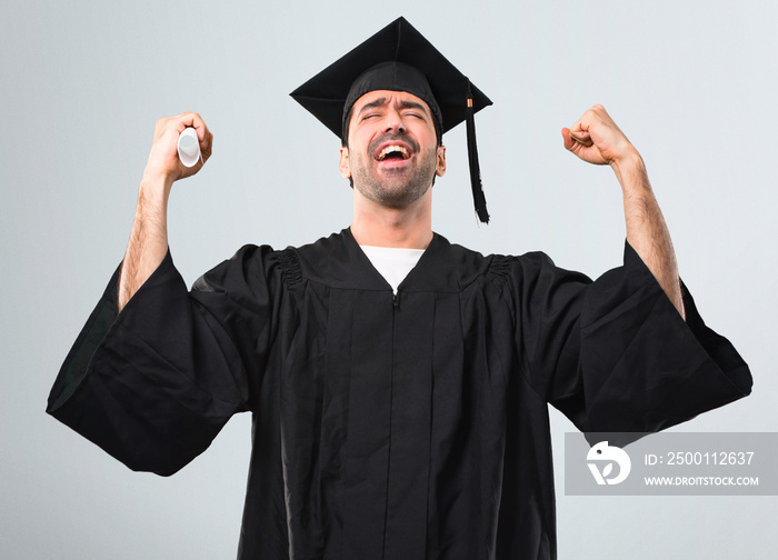 Man on his graduation day University celebrating a victory in winner position on grey background