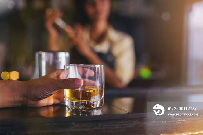 Glass handles are placed on the bar in the night club. There is a bartender standing by for service as background.