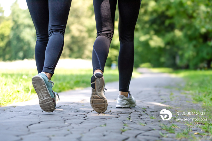 Wellness and fitness concept - low angle view of running women in the park on a sunny morning.