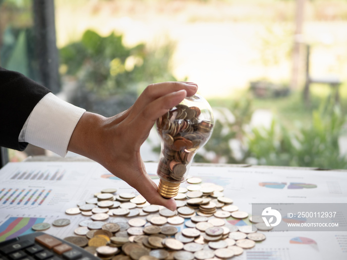 Hands of businessman holding a light bulb with coin. The idea of ​​reducing costs and reduce energy consumption and energy savings