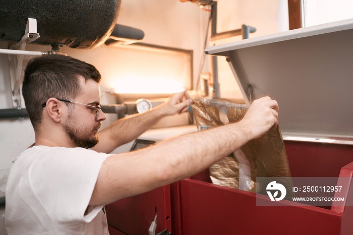 Man loading pellet stove with granule bag