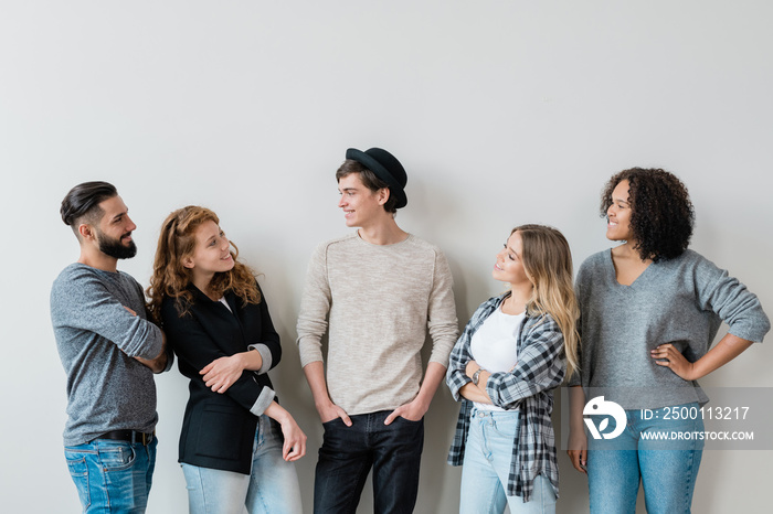 Five casual carefree guys and girls having friendly talk at leisure