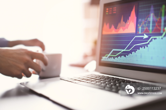 Laptop with stock data on table in office. Financial trading concept