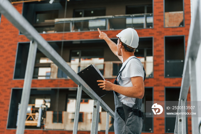 Manager of project. Young man working in uniform at construction at daytime