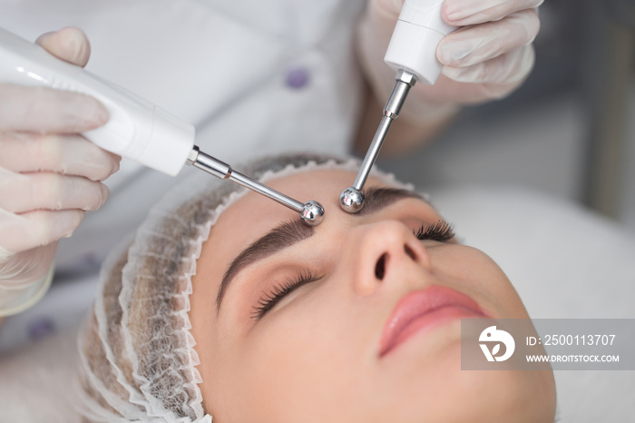 Macro close up portrait of woman having cosmetic galvanic beauty treatment in spa.Therapist applying low frequency current with electrodes on face