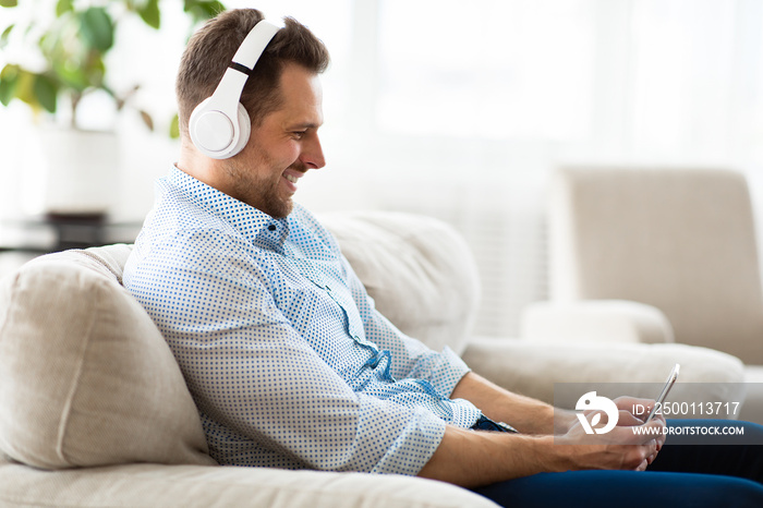 Happy guy listening to music sitting on sofa