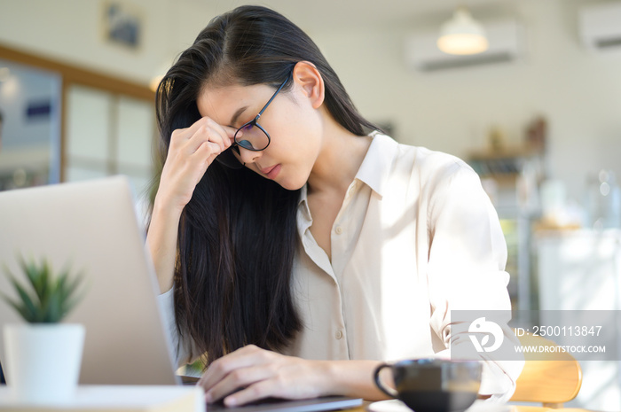 Tired and stressed business woman with headache from using laptop in coffee shop