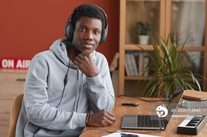 Portrait of young African-American musician looking at camera and using laptop while making music at home, copy space