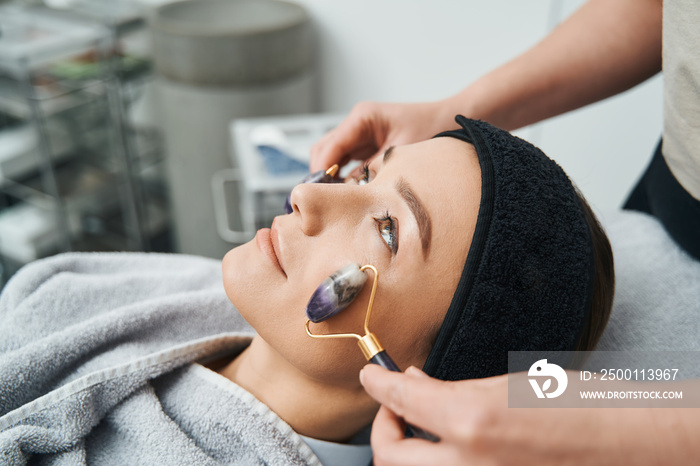 Woman being massaged with a pair of amethyst face rollers