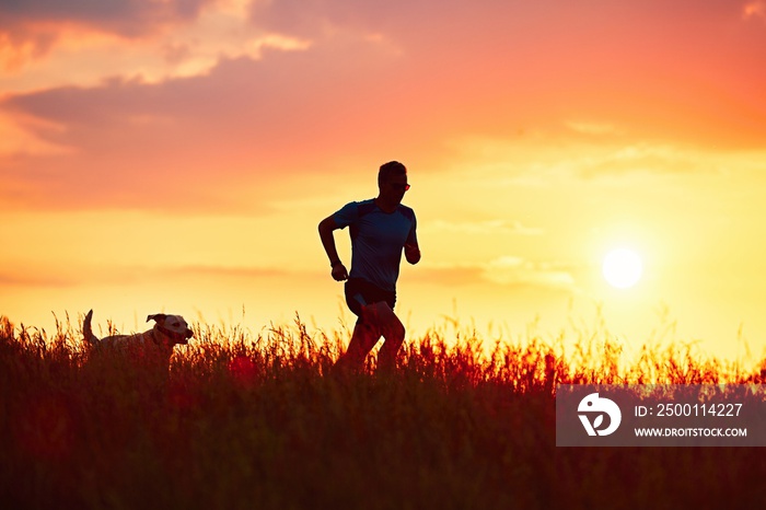 Athletic runner with dog at the sunset