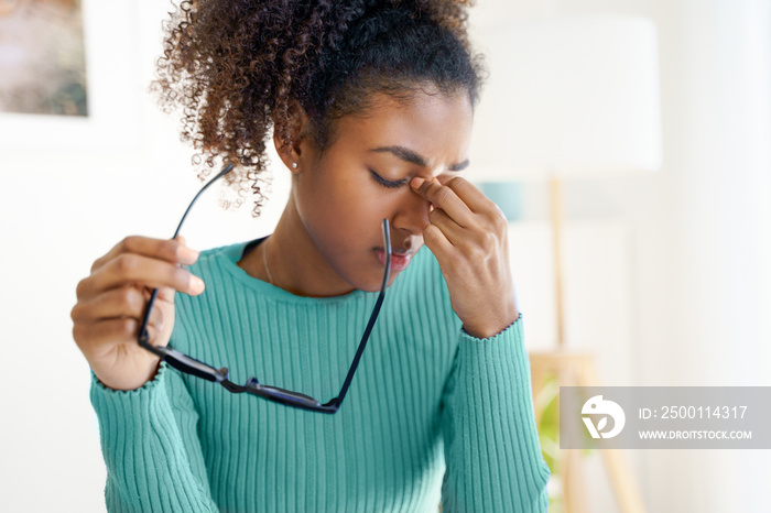 Overworked african student woman with headache at home