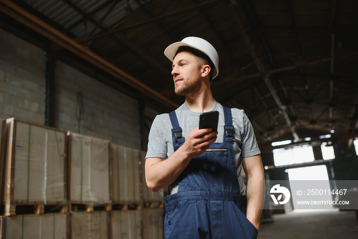 Management team, engineer, or foreman. Standing checking job information about industrial production management within the factory by phone. Teamwork concept