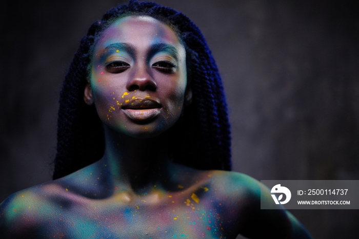 African woman with colourful powder on her face and body.