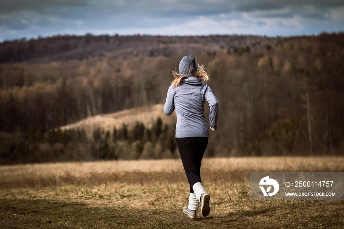 Woman running in autumn nature. Fitness activity outdoors