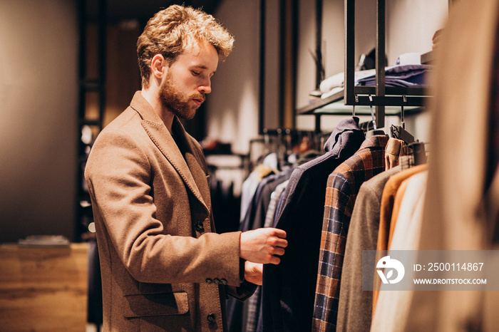 Young handsome man choosing cloth at shop