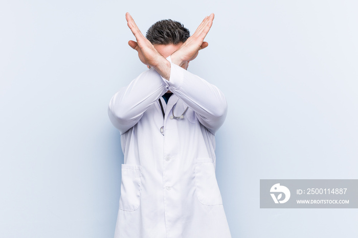 Young handsome doctor man keeping two arms crossed, denial concept.