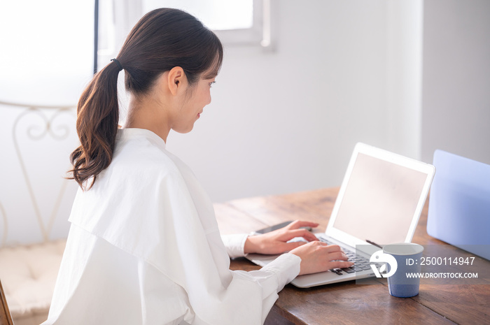 Back view of a beautiful Asian (Japanese) woman working on her laptop.