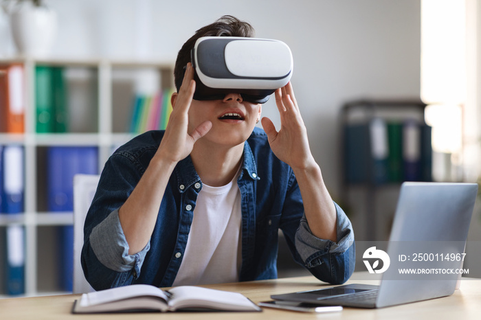 Young Male Office Employee Using VR Glasses While Sitting At Desk