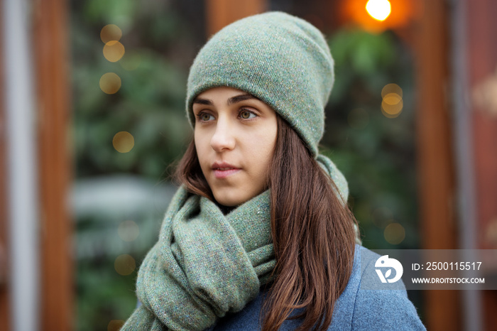 Portrait of a girl in a green hat and scarf, a walk through the Christmas city, a smile on her face, cool weather, a fascinating looking off to the side