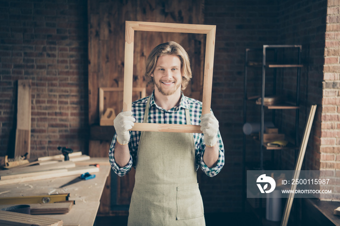 Portrait of his he nice attractive handsome blond cheerful cheery creative artisan guy artist holding in hands new smooth frame at industrial brick loft style interior workplace